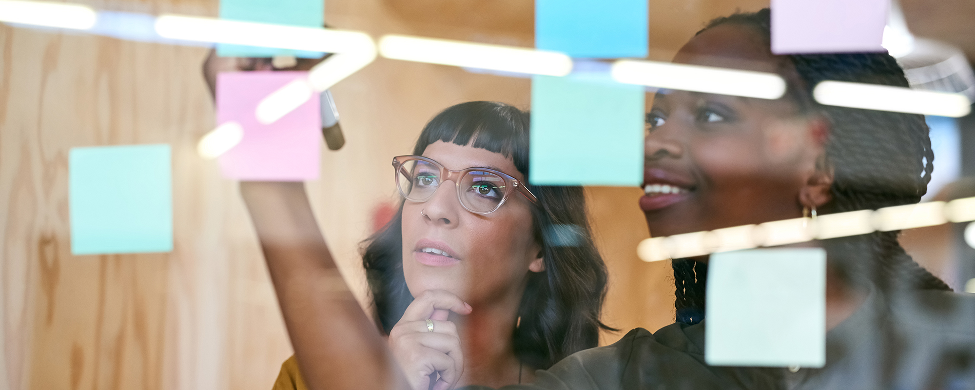 Two women writing on sticky notes