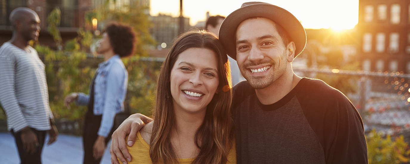 A man and a woman smiling in front of a sunset