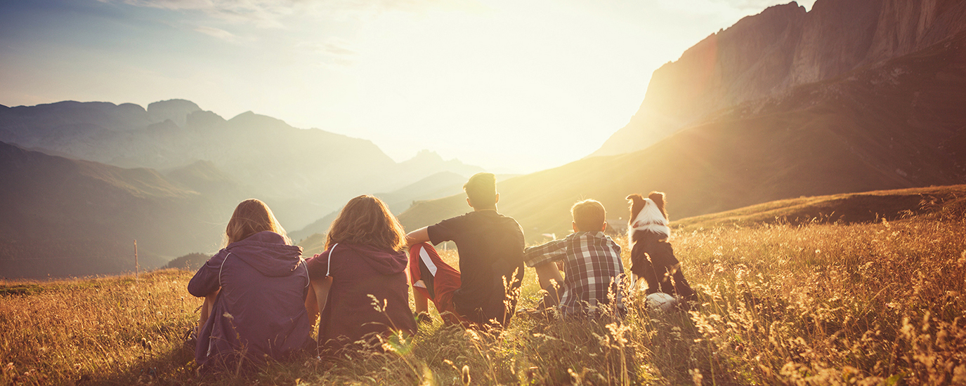 A group of friends on a hike admiring the sun setting over some mountains