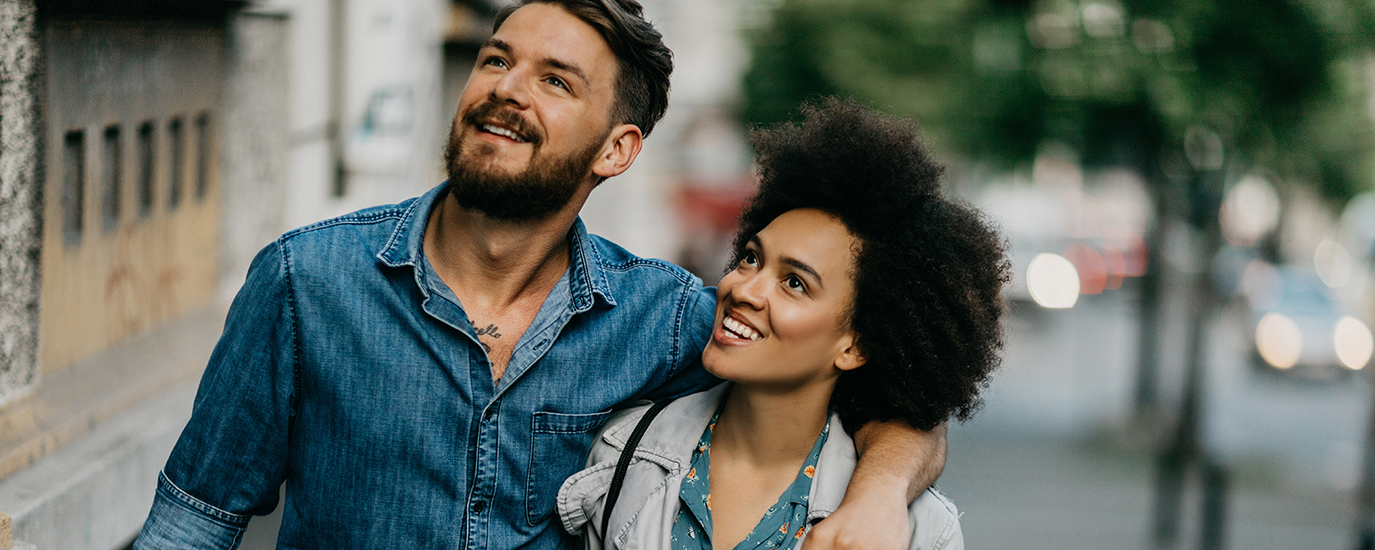 A man and woman outdoors and smiling and gazing towards the sky